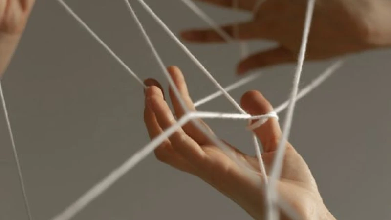 Hands holding white threads stretched between the fingers