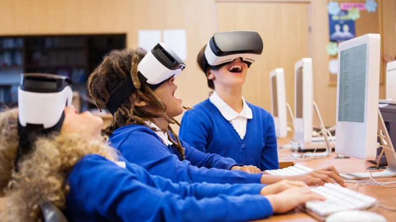 Students wearing VR headsets at computers in a classroom