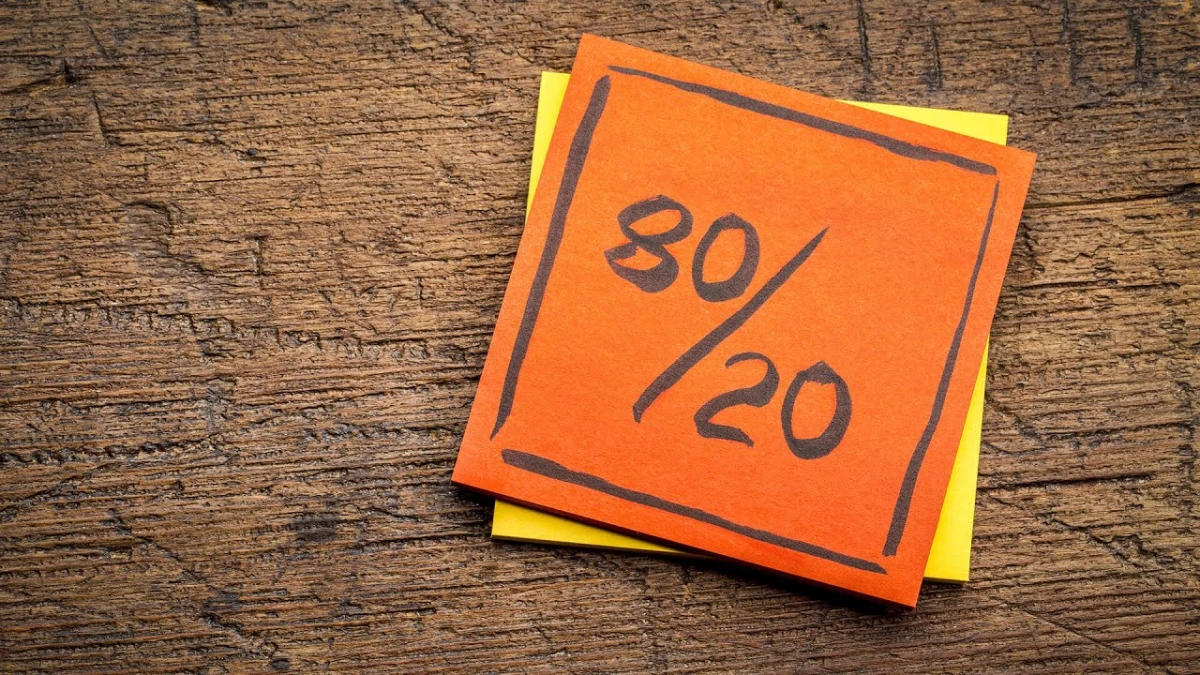 An orange note with 80/20 written on it on a wooden surface