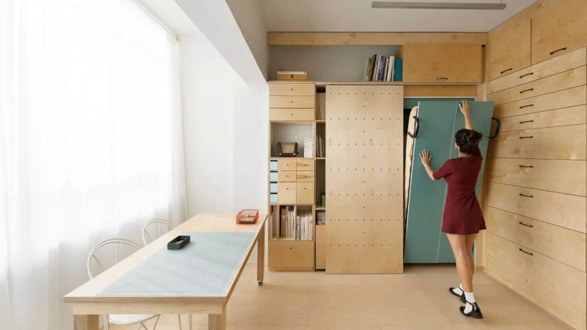 A woman beside built-in storage in a bright room with wooden furniture
