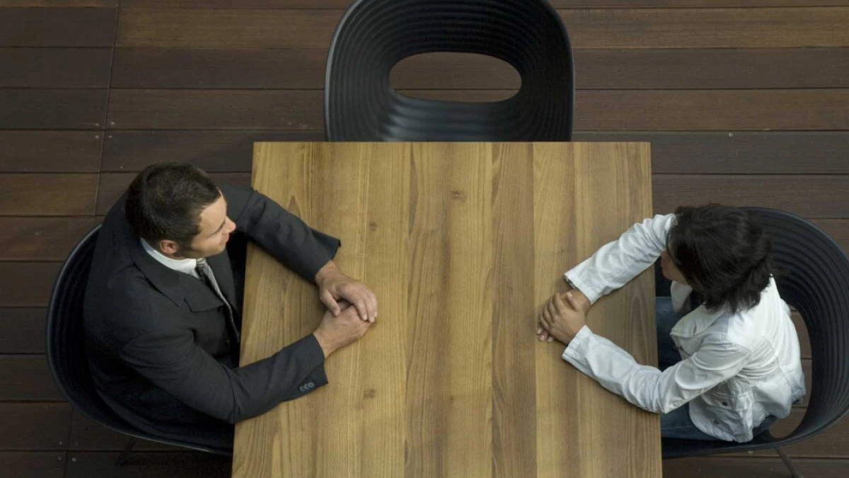 Overhead view of two people sitting opposite each other at a wooden table