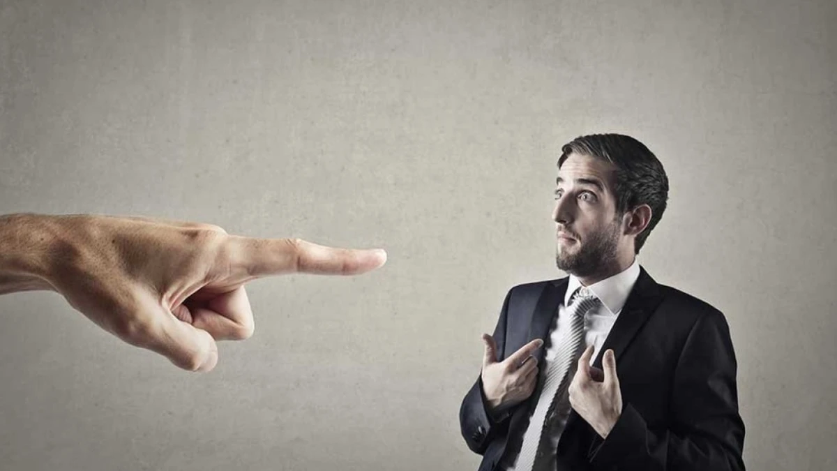 A large pointing hand directed at a man in a suit
