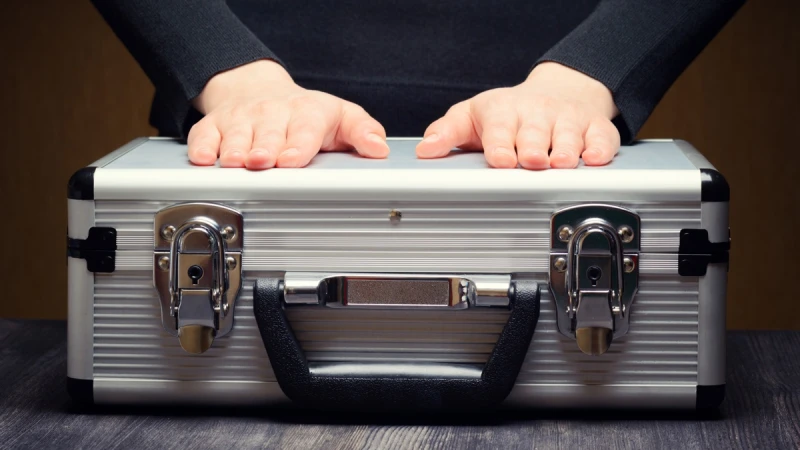 Two open hands above a closed metal briefcase