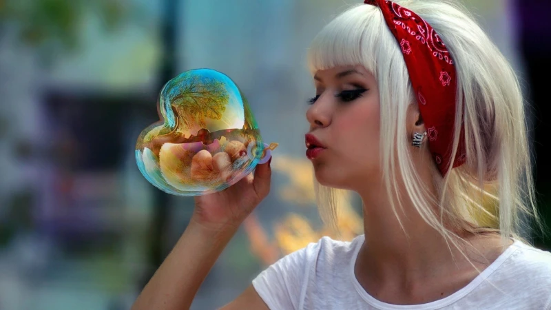 A woman with a red headband blowing a heart-shaped bubble